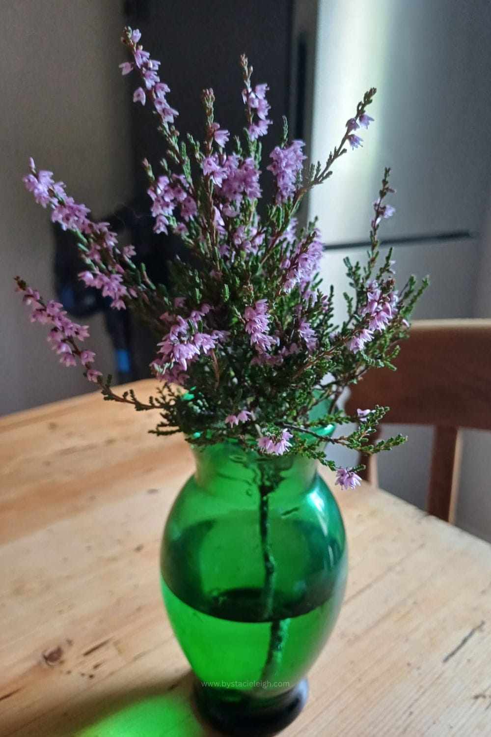 Fresh heather in a green glass vase on a wooden table, Scottish home